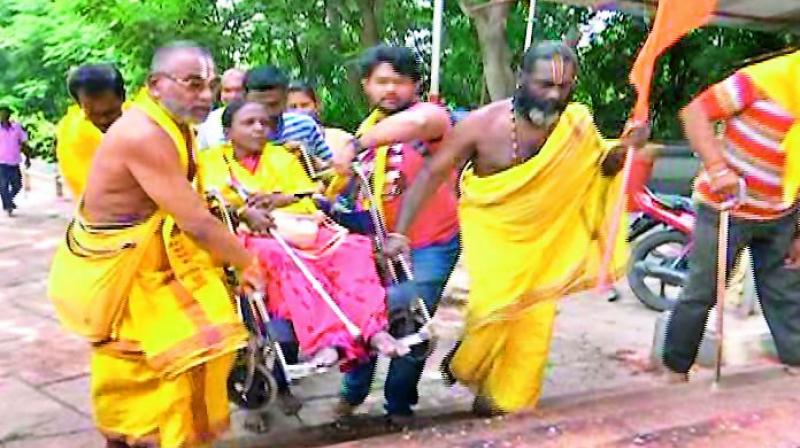 A group of volunteers carry a wheelchair-bound devotee to Tirumala on Monday.