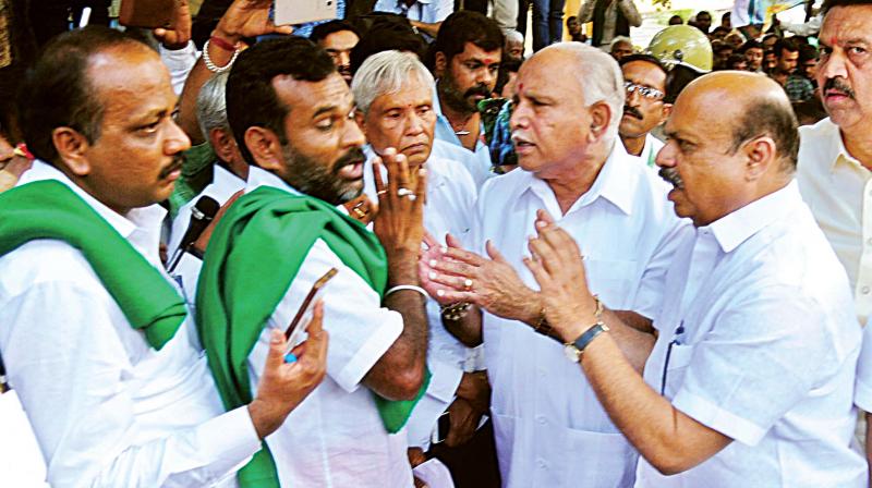 BJP leaders B.S. Yeddyurappa, Basavaraj Bommai and Ramachandra Gowda try to pacify agitating farmers in front of the party office in Malleswaram in Bengaluru on Tuesday.