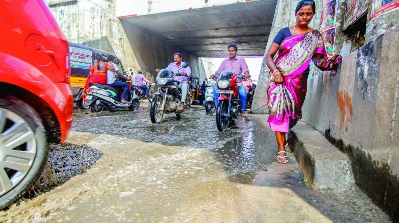 Pedestrians and two-wheelers crossing the rail under the bridge flooded with drain water. (Photo: DC)