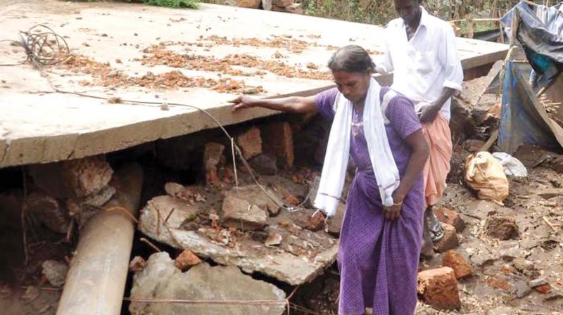 Karthikeyan and wife in front of their house which sank at Cheriya Tekkanam in Kunnukara panchayat during the flood. (File pic)