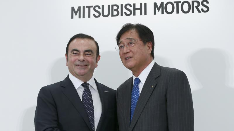 Nissan Motor Co. CEO Carlos Ghosn, left, and Mitsubishi Motors Corp. CEO Osamu Masuko pose for photographers during a joint press conference in Tokyo. (Photo: AP)