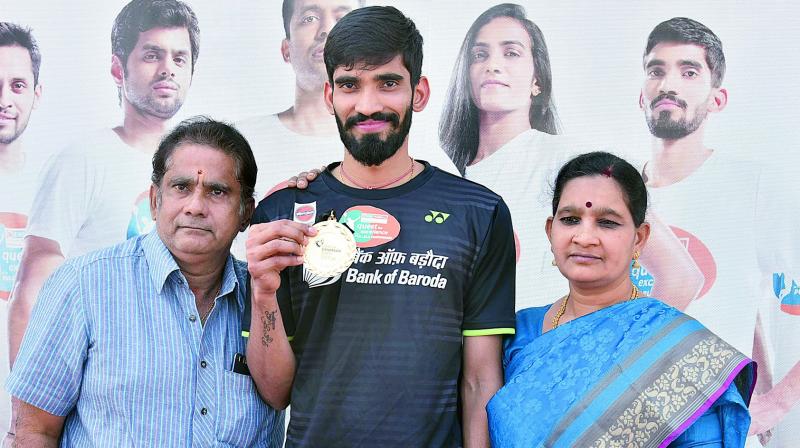 Srikanth Kidambi shows off his Denmark Open winners medal as he poses along with his parents at the Pullela Gopichand Badminton Academy in Hyderabad on Tuesday.
