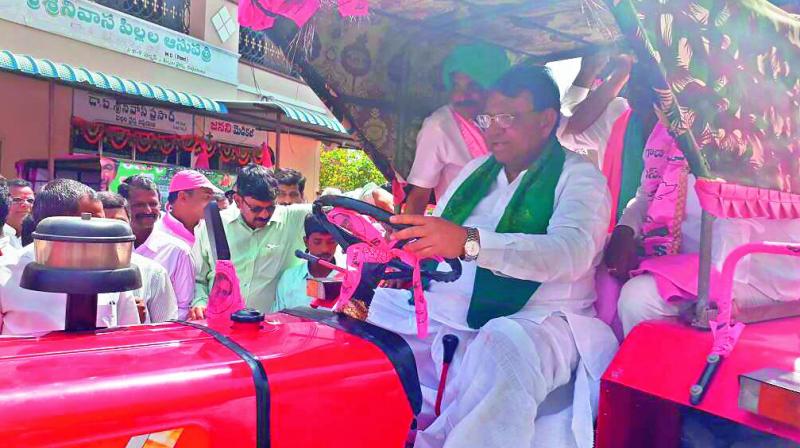 Minister Pocharam Srinivas Reddy drives a tractor from Banswada to Warangal on Wednesday to attend the TRS meeting. (Photo: DC)