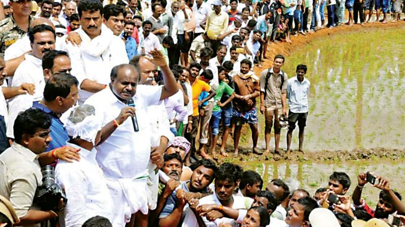 Chief Minister H.D. Kumaraswamy addresses  farmers before planting paddy at Seethapura in Pandavapura taluk on Saturday.
