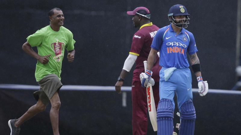 Indias captain Virat Kohli, right, leaves the field as rain delays the first ODI cricket match against West Indies at Queens Park Oval in Port of Spain (Photo: AP) (Photo: AP)