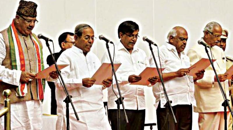 Excise Minister H.Y. Meti (second from left) and primary and secondary education minister Tanveer Sait (left) who is involved in the porn controversy,  during the swearing-in ceremony four months ago.