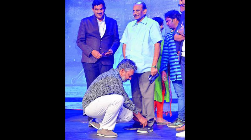 l Rajamouli tying the laces of his father Vijayendra Prasads shoes