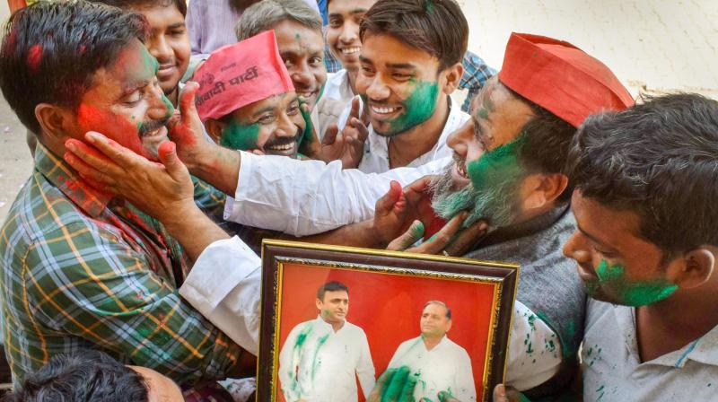 Samajwadi Party supporters apply gulal on a photo of SP chief Akhilesh Yadav and party founder Mulayam Singh Yadav as they celebrate their lead in Phulpur and Gorakhpur Lok Sabha by-poll election, in Allahabad. (Photo: PTI)