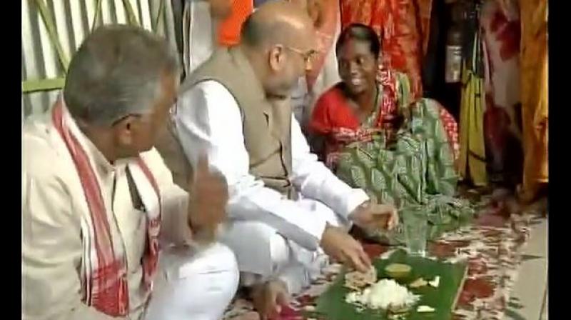 BJP President Amit Shah eating lunch at the house of a tribal family in Naxalbari, West Bengal. (Photo: ANI/Twitter)