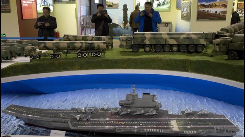 Visitors take photos near models of Chinese ballistic missiles and aircraft carrier at an exhibition highlighting Chinas achievements, in Beijing. (Photo: AP File)