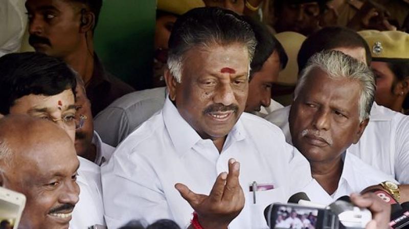 Tamil Nadu Chief Minister O Panneerselvam, flamke by supporters, addresses a press conference at his residence in Chennai on Wednesday. (Photo: PTI)