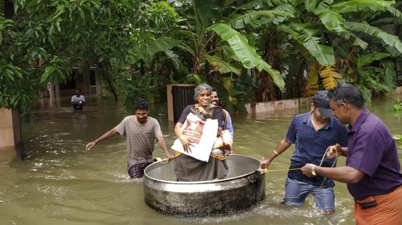 An elderly woman is rescued in a cooking utensil after her home was flooded in Thrissur, Kerala. (Photo: AP)