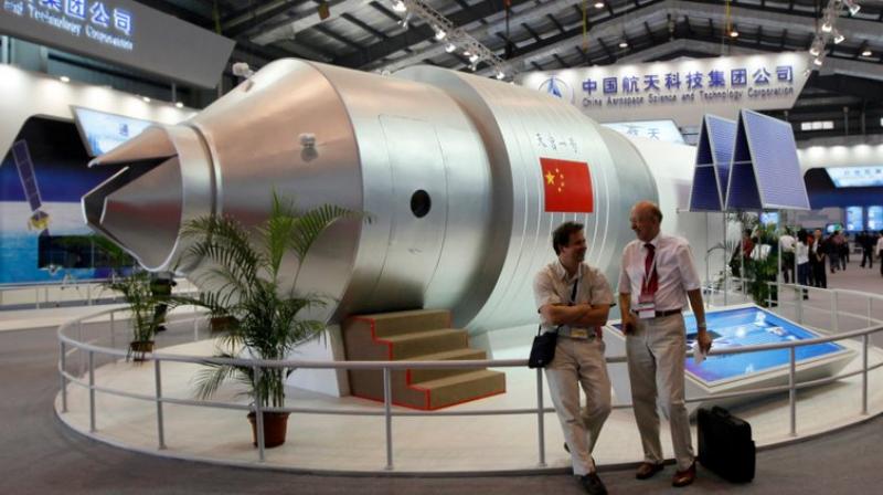 This file photo shows visitors sit beside a model of Chinas Tiangong-1 space station at the 8th China International Aviation and Aerospace Exhibition in Zhuhai in southern Chinas Guangdong Province. (AP Photo/Kin Cheung, File)