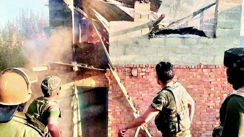 Security forces personnel douse the fire at the slain PDP leaders house that was allegedly torched by a mob, in Srinagar on Tuesday. (Photo: PTI)
