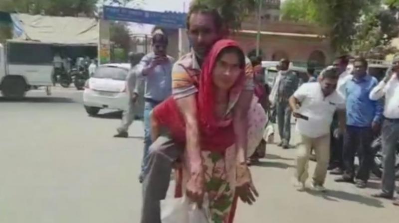 Vimla Devi carrying her husband Badan Singh on her back in Mathura. (Photo: ANI | Twitter)