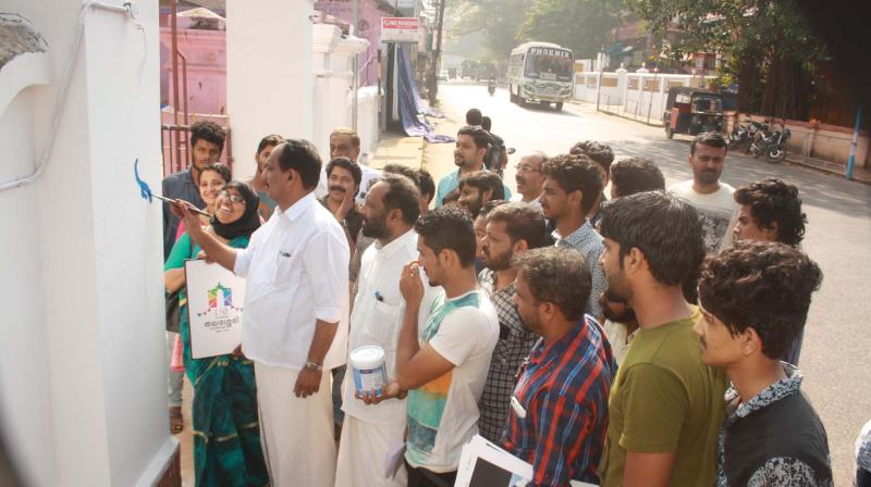 Thalassery municipal chairman C.K. Rameshan paints the wall as part of the project. (Photo: DC)