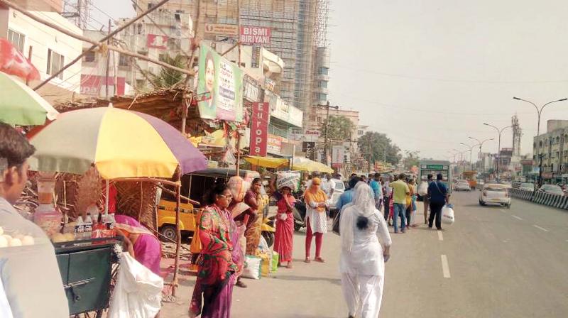 Commuters wait by the roadside near Velachery in the absence of a bus shelter. (Photo: DC)