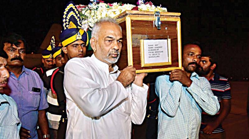 Hassan district incharge minister A. Manju carries body of sepoy Sandeep at KIA in Bengaluru on Tuesday. (Photo: DC)