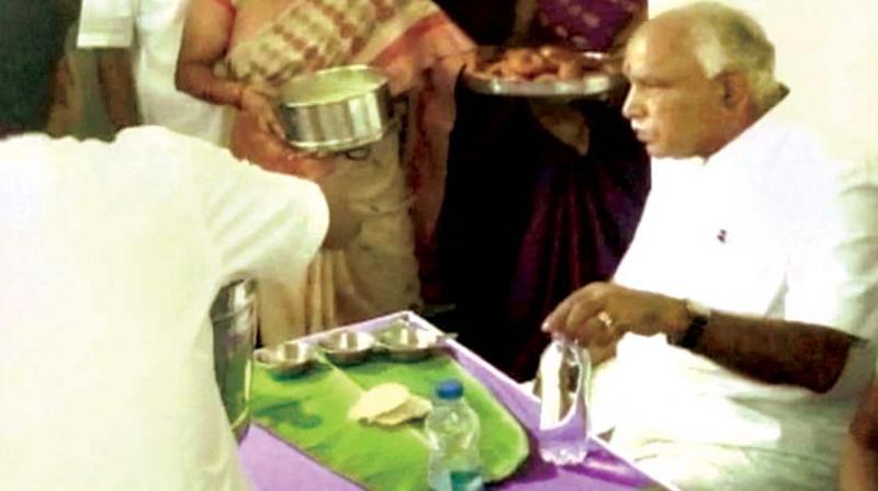 A file photo of BJP state president B.S. Yeddyurappa having food during a visit to a Dalit home