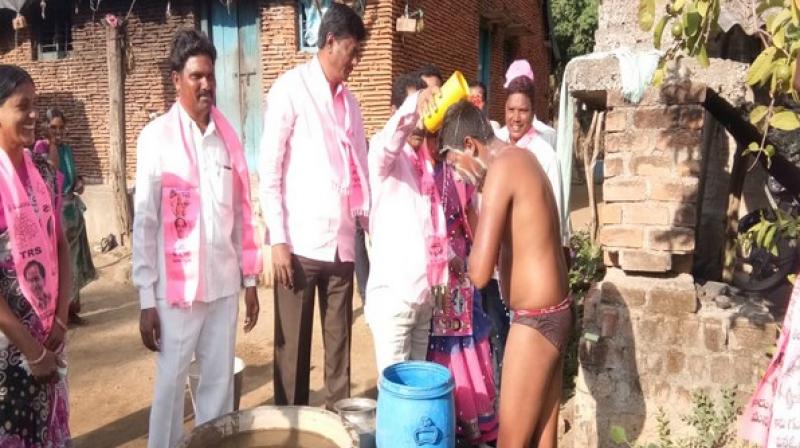 TRS leader Koram Kanakaiah from Yellandu constituency was seen helping a person take bath by pouring water on his head with a mug. (Photo: ANI)