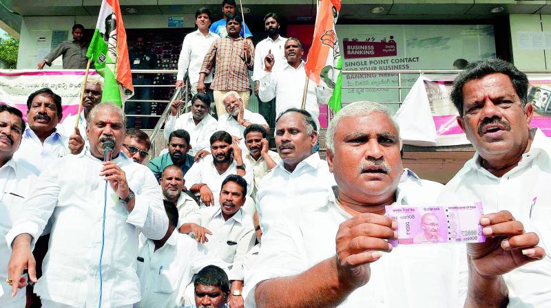 Congress leaders stage dharna in front of a corporate bank protesting against the inconvenience caused due to demonetisation, in Vijayawada on Monday. (Photo: DC)