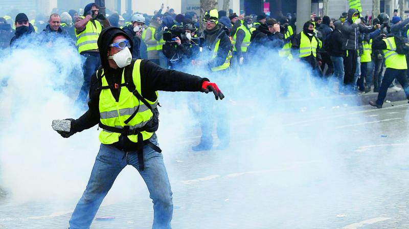 A protester wearing a yellow vest (Gilet jaune) throws a cobble at police forces near the Champs Elysees in Paris on Saturday. (Photo: AFP)