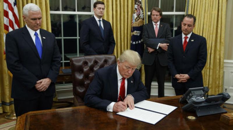 Vice President Mike Pence watches at left as President Donald Trump prepares to sign his first executive order in the Oval Office of the White House in Washington. (Photo: AP)