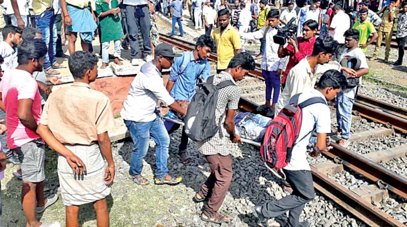 Commuters and students take one of the injured persons out of the railway track in Chennai on Tuesday (Photo: DC)