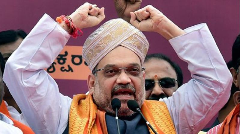 BJP president Amit Shah wears a Mysore Peta, a traditional headgear, upon his arrival on a three-day visit to Karnataka as part of his 110-day nationwide tour, in Bengaluru on Saturday. (Photo: PTI)