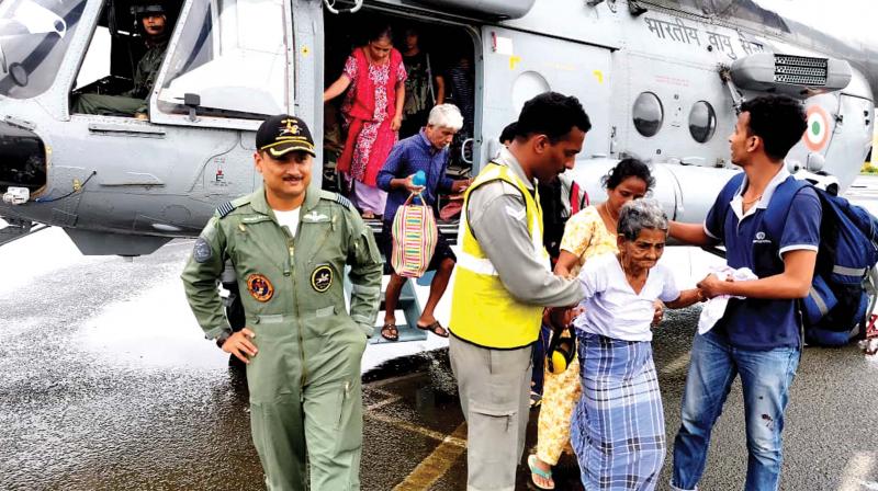 Indian Air Force personnel bring an old woman who was stranded in the flood in Pathanamthitta to Thiruvananthapuram on an helicopter on Thursday
