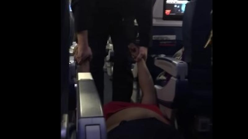 A video posted online shows uniformed officers dragging the woman down the aisle as seated passengers watched. (Photo: Videograb)