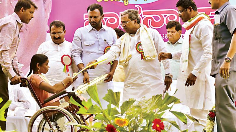 CM Siddaramaiah with a physically challenged beneficiary at Teradal on Tuesday. (Photo: DC)