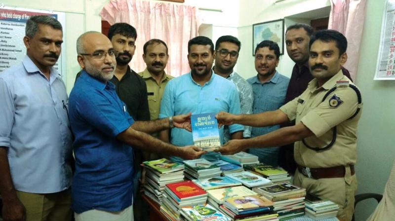 Relatives of Mufeed and Muneer, victims of road accident, hand over the first set of books to Panur SI M.S. Faizal on Friday.