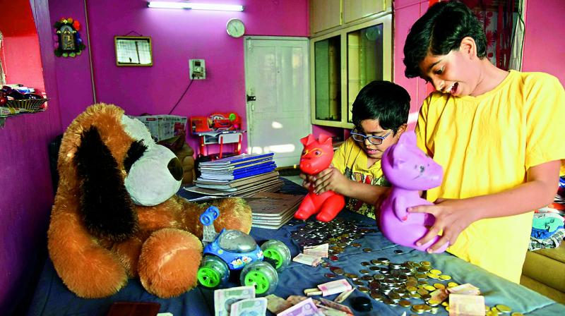 Children break their piggy banks to provide smaller denomination notes to their family, in Hyderabad on Wednesday. 	(Photo: DC)