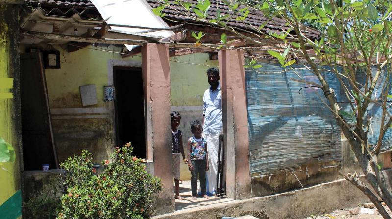 Subrahmanyam and children in front their damaged house.