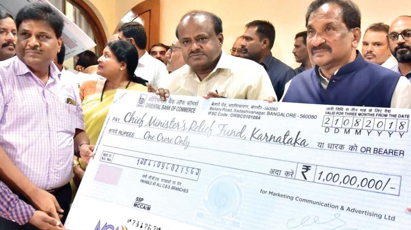 CM H.D. Kumaraswamy and  Minister K.J. George receive a cheque for 1 crore for CMs relief fund for Kodagu flood victims, in Bengaluru on Tuesday  	 DC