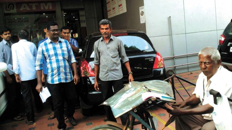 Paraplegic lottery vendor P.V. Rajan steers his  tricycle out of bank premises at Statue Junction after exchanging currency notes on Thursday.