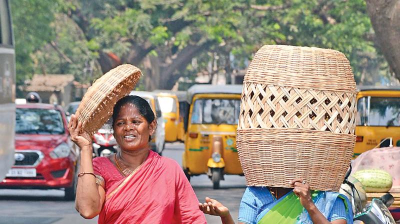 Two women cover themselves using bamboo baskets to escape heat at Chetpet. (Photo: DC)