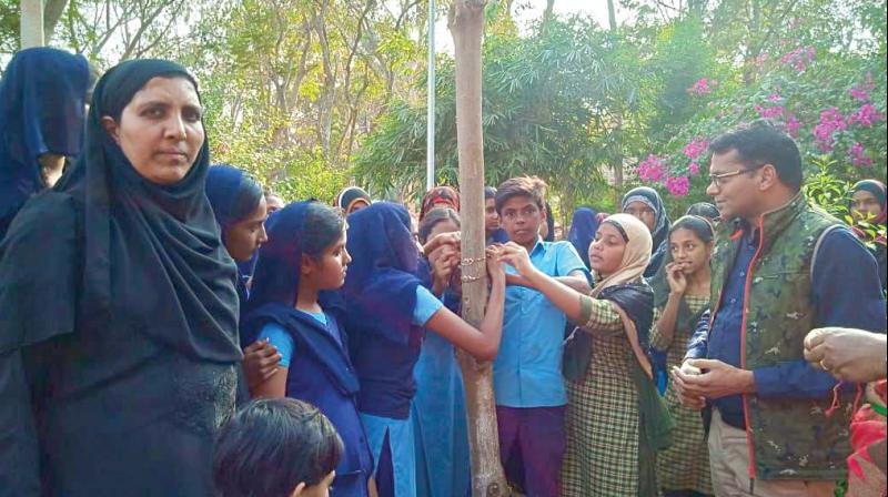 Students of the Government Urdu High School tie rakhis to a tree in Kollegal on Saturday 	 DC