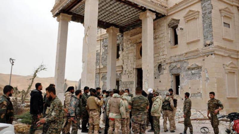 Syrian government soldiers gather outside a damaged palace, in Palmyra, central Syria. (Photo: AP)