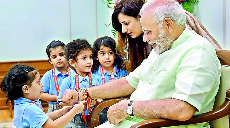 Children tie rakhi on Prime Minister Narendra Modi on the occasion of Raksha Bandhan in New Delhi on Sunday. (Photo: PTI)