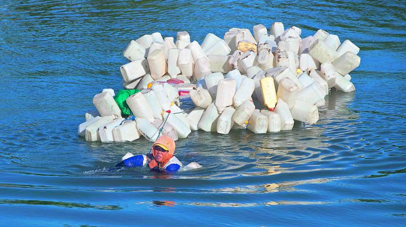 Indonesian Hasria swimming with hundreds of jars tied to her back to get clean water in Tinambung, West Sulawesi. (Photo: AFP)