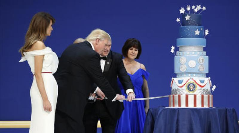 First lady Melania Trump watches as President Donald J. Trump, and Vice President Mike Pence, right,are helped by Coast Guard Petty Officer 2nd Class Matthew Babot, center, as they cut a cake at The Salute To Our Armed Services Inaugural Ball. (Photo: AP)