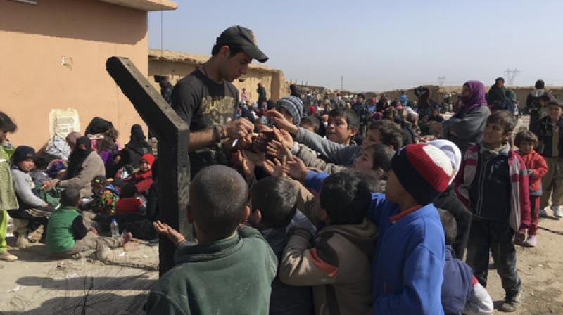 An Iraqi Army soldier distributes candies to displaced children as they flee their homes due to fighting between Iraqi security forces and Islamic State militants, on the western side of Mosul. (Photo: AP)