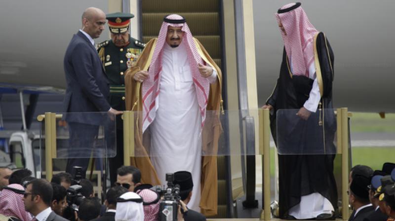 Saudi King Salman adjusts his headscarf as he steps down the stairs of his plane upon arrival at Halim Perdanakusuma Airport in Jakarta. (Photo: AP)
