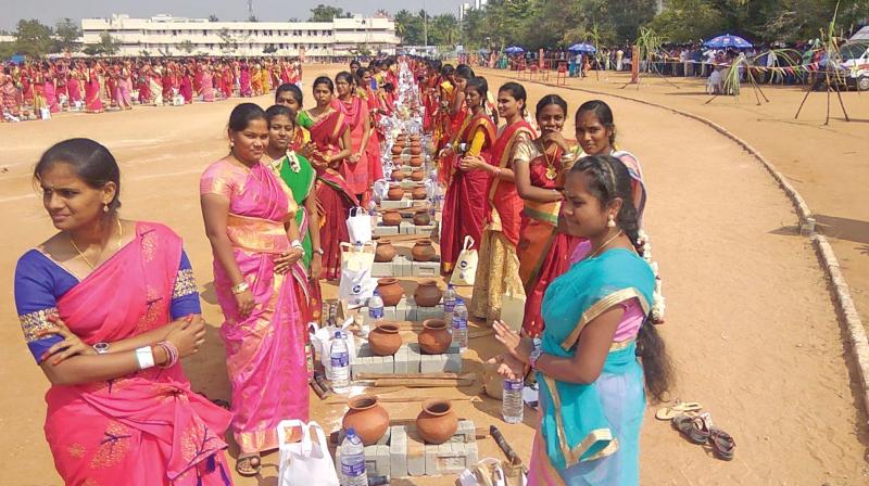 Woman students line up with earthen pots to make sweet Pongal on the college campus on Friday. 	(DC)