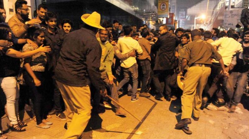 Policemen cane revellers who gathered at MG Road and Brigade Road to celebrate New Year (Photo: DC)