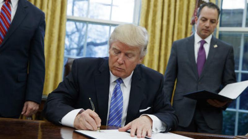 President Donald Trump signs an executive order to withdraw the US from the 12-nation Trans-Pacific Partnership trade pact agreed to under the Obama administration in the Oval Office of the White House in Washington. (Photo: AP)