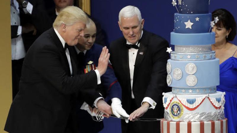 First lady Melania Trump watches as President Donald J. Trump, and Vice President Mike Pence, right, are helped by Coast Guard Petty Officer 2nd Class Matthew Babot, center, as they cut a cake at The Salute To Our Armed Services Inaugural Ball. (Photo: AP)