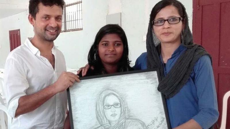 Shemi and husband Faslu receive the pencil sketch from Deepa (middle).